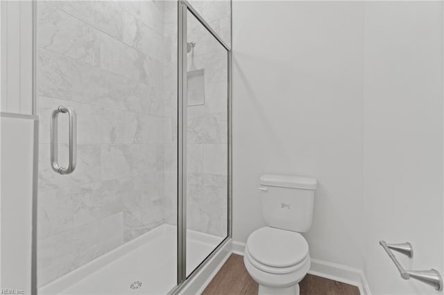 bathroom with wood-type flooring, an enclosed shower, and toilet