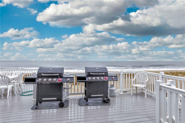 deck with grilling area, a beach view, and a water view