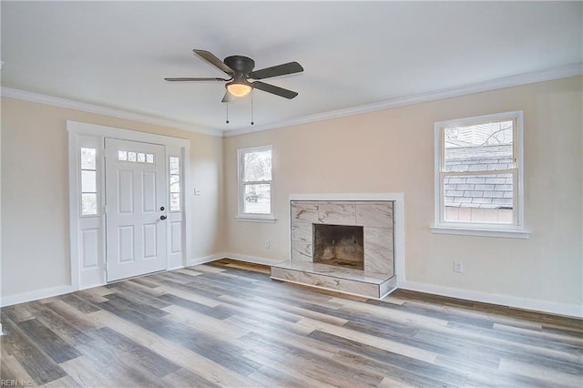 unfurnished living room with hardwood / wood-style flooring, ceiling fan, ornamental molding, and a tiled fireplace