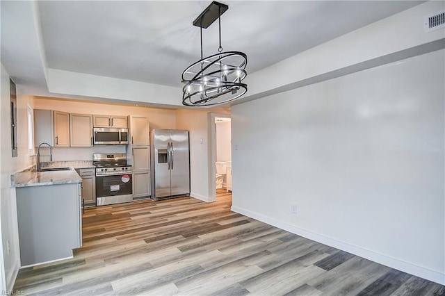 kitchen with light stone counters, sink, stainless steel appliances, and light wood-type flooring