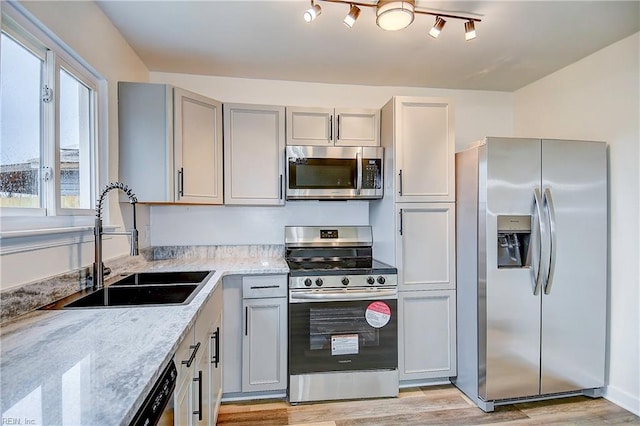 kitchen with sink, light hardwood / wood-style flooring, gray cabinets, stainless steel appliances, and light stone countertops