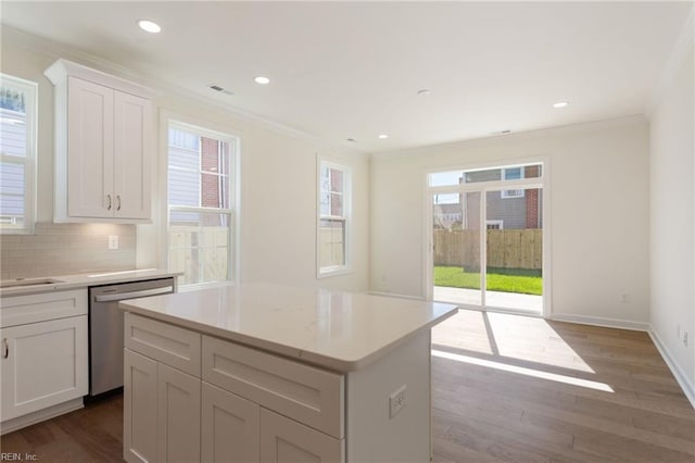 kitchen with white cabinetry, backsplash, hardwood / wood-style flooring, a center island, and stainless steel dishwasher