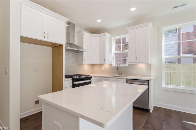 kitchen with wall chimney exhaust hood, sink, a kitchen island, stainless steel appliances, and white cabinets