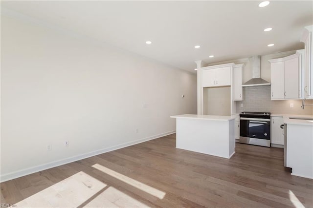 kitchen featuring white cabinets, a kitchen island, stainless steel range oven, and wall chimney exhaust hood