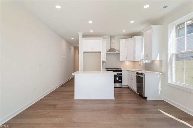 kitchen featuring white cabinets, a center island, wall chimney exhaust hood, and appliances with stainless steel finishes