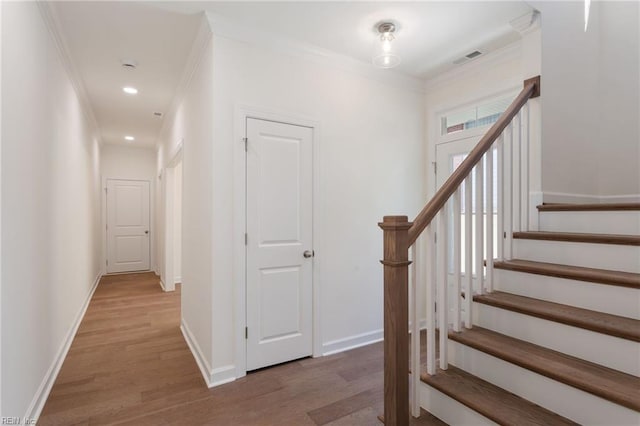 stairway with hardwood / wood-style flooring and ornamental molding