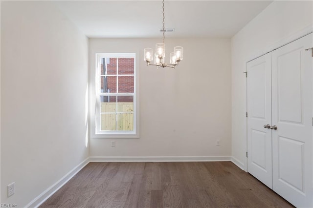 unfurnished dining area featuring dark hardwood / wood-style floors and a chandelier