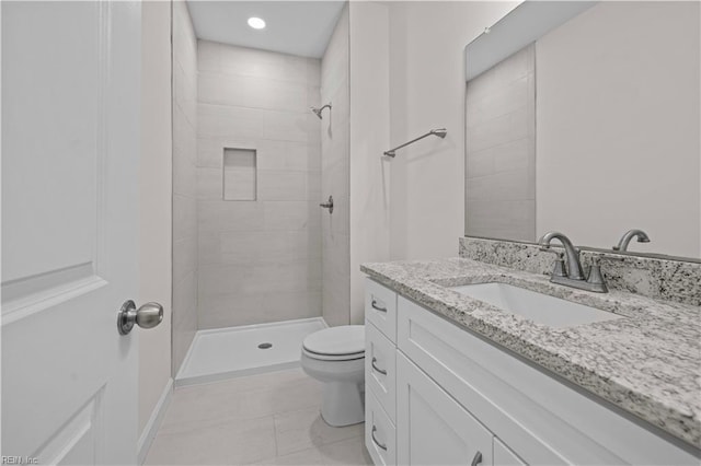 bathroom featuring vanity, tile patterned flooring, toilet, and a tile shower