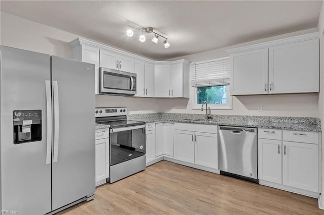 kitchen with sink, white cabinets, light hardwood / wood-style floors, stainless steel appliances, and light stone countertops