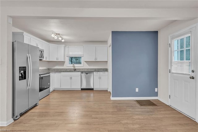 kitchen featuring sink, white cabinetry, stainless steel appliances, light stone counters, and light wood-type flooring