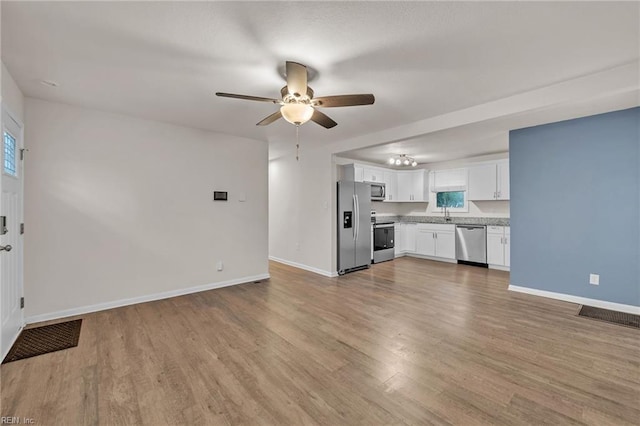 unfurnished living room featuring ceiling fan, sink, and light hardwood / wood-style flooring