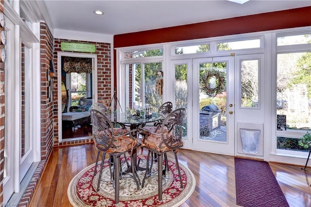 dining area with wood-type flooring and brick wall