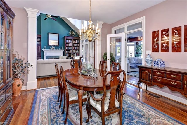 dining room featuring hardwood / wood-style flooring, a chandelier, and ornate columns