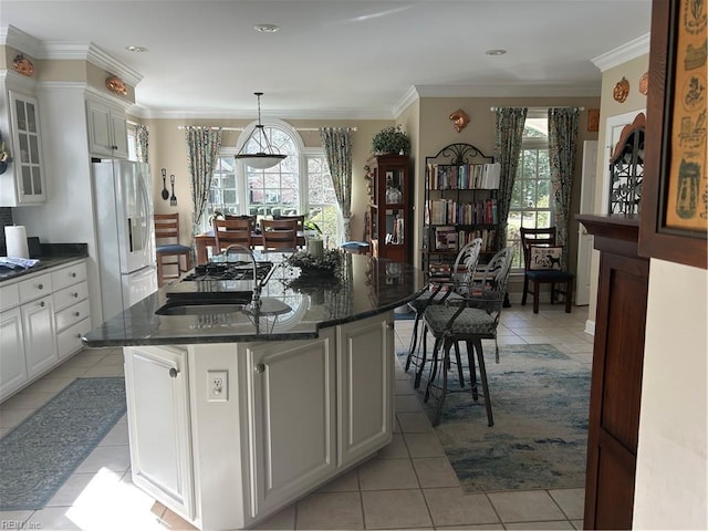 kitchen featuring a healthy amount of sunlight, a kitchen island with sink, white fridge with ice dispenser, and white cabinets