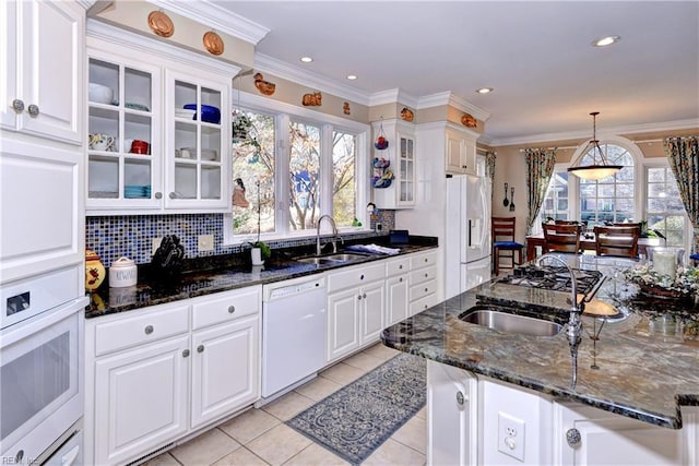 kitchen with white cabinetry, white appliances, sink, and dark stone countertops