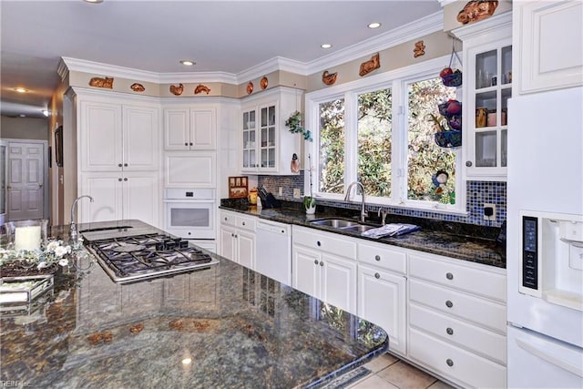 kitchen featuring sink, white cabinets, white appliances, and dark stone counters