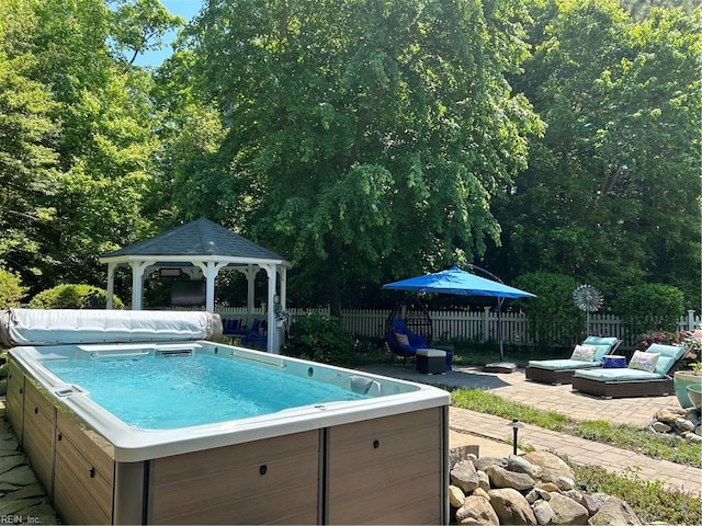 view of swimming pool with a hot tub, a gazebo, and a patio