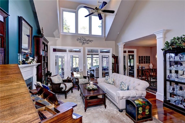 living room with decorative columns, hardwood / wood-style floors, a wealth of natural light, and ceiling fan