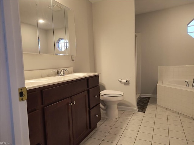 bathroom with a relaxing tiled tub, tile patterned floors, toilet, and vanity