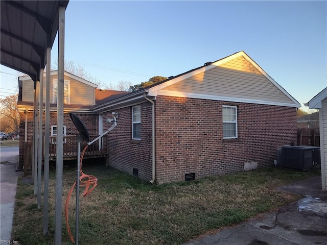 view of side of home featuring a carport, a lawn, and central air condition unit