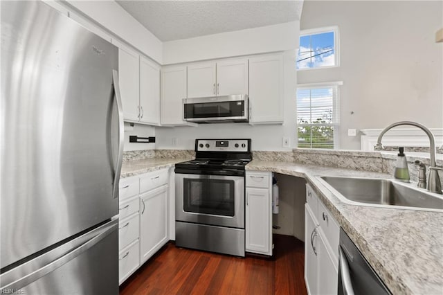 kitchen featuring sink, white cabinetry, a textured ceiling, appliances with stainless steel finishes, and dark hardwood / wood-style flooring