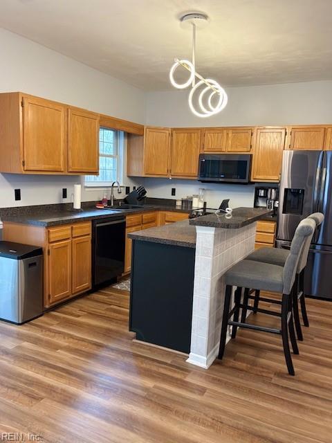 kitchen with dishwasher, sink, hanging light fixtures, hardwood / wood-style flooring, and stainless steel fridge with ice dispenser