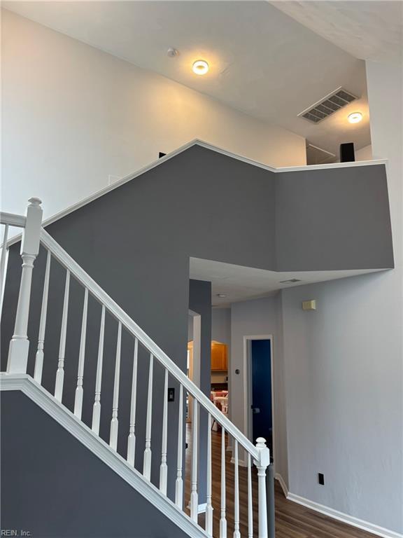 staircase with a towering ceiling and wood-type flooring