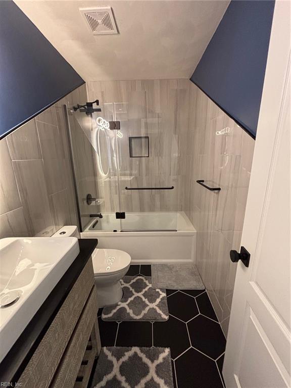 full bathroom featuring tiled shower / bath, tile walls, vanity, toilet, and tile patterned floors