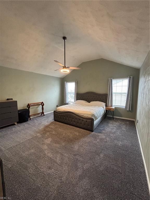 bedroom featuring multiple windows, vaulted ceiling, and dark colored carpet