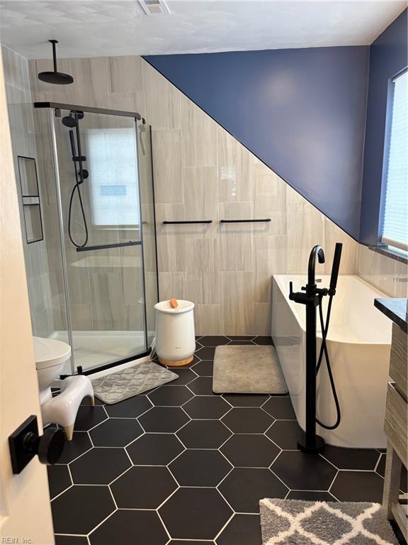 bathroom featuring separate shower and tub, tile walls, and toilet