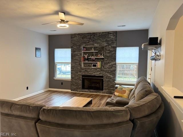 living room featuring a stone fireplace, ceiling fan, and hardwood / wood-style flooring