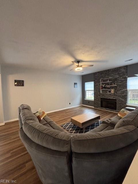 living room featuring hardwood / wood-style floors, a stone fireplace, and ceiling fan