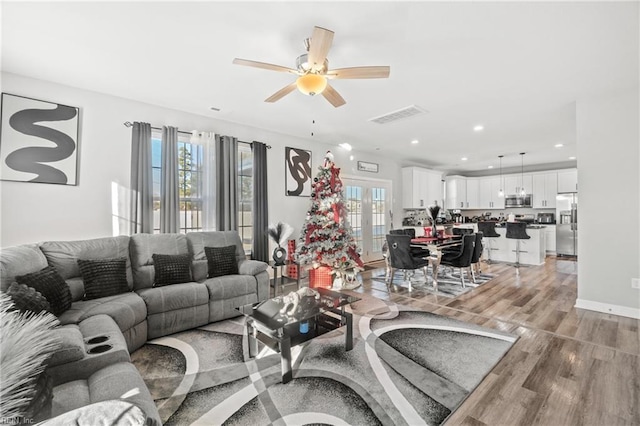 living room with french doors, ceiling fan, and light hardwood / wood-style flooring