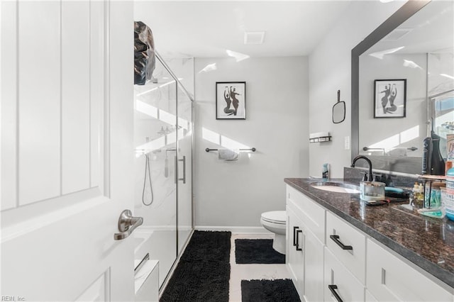 bathroom featuring a shower with door, vanity, and toilet