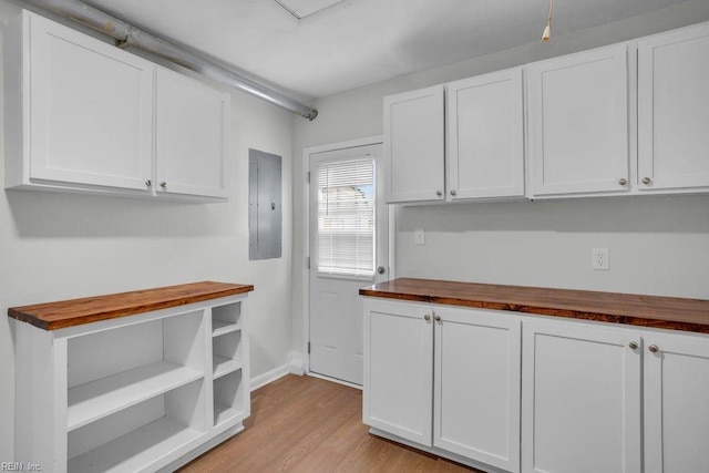 kitchen featuring white cabinetry, butcher block counters, and electric panel