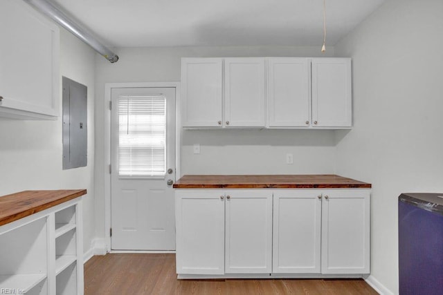 kitchen with electric panel, butcher block countertops, and white cabinets