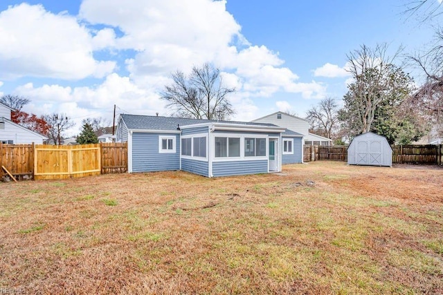 rear view of property featuring a sunroom, a storage unit, and a lawn