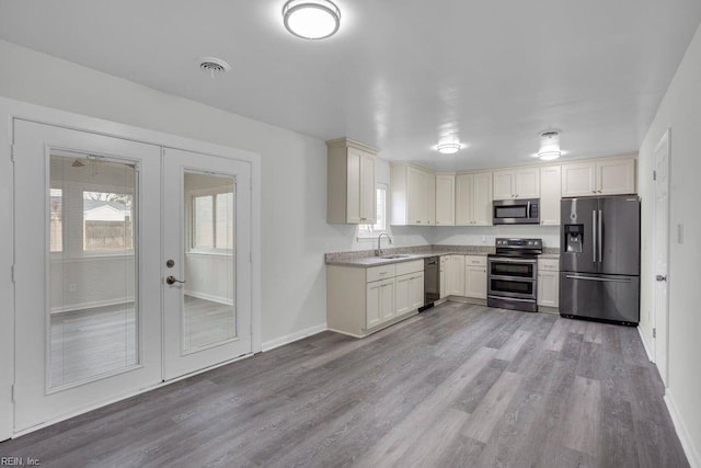 kitchen featuring appliances with stainless steel finishes, sink, light hardwood / wood-style floors, and french doors