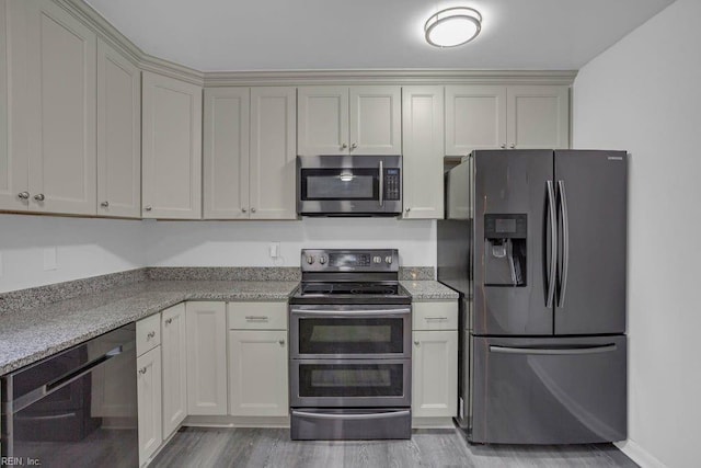 kitchen featuring stainless steel appliances, light stone countertops, light hardwood / wood-style floors, and cream cabinetry