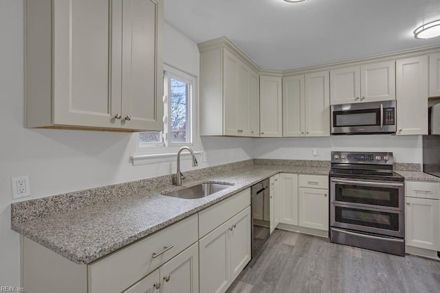 kitchen featuring light stone counters, sink, light hardwood / wood-style flooring, and stainless steel appliances