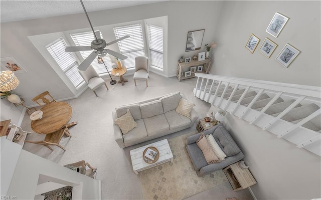 carpeted living room featuring ceiling fan and a textured ceiling