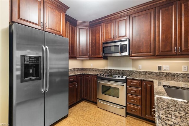 kitchen featuring stainless steel appliances, sink, and dark stone countertops