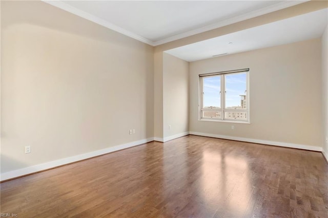 empty room with hardwood / wood-style flooring and crown molding