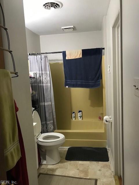 bathroom featuring shower / tub combo with curtain and toilet