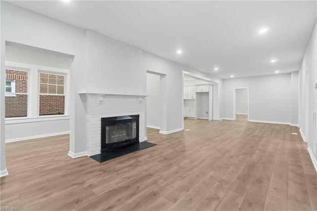 unfurnished living room featuring a fireplace and light hardwood / wood-style floors