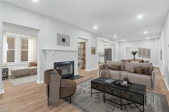 living room with a brick fireplace and light wood-type flooring