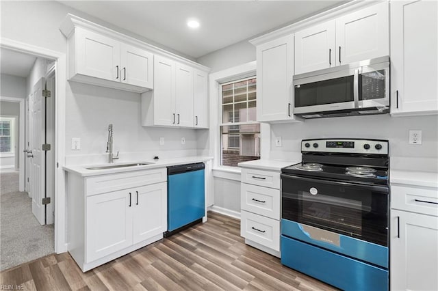 kitchen with white cabinetry, stainless steel appliances, sink, and wood-type flooring