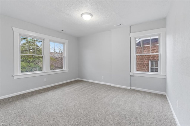 carpeted empty room with a textured ceiling