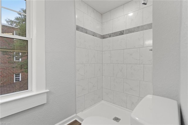 bathroom featuring a tile shower and toilet