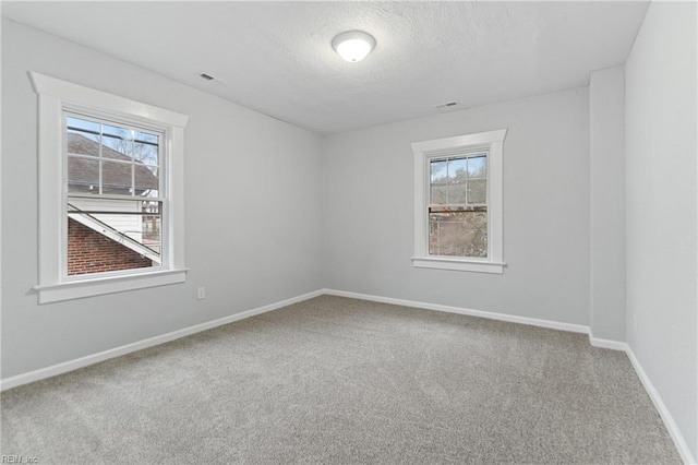 carpeted spare room with a textured ceiling